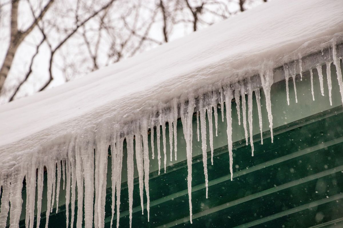 Icicles hanging from a snow-covered roof edge.